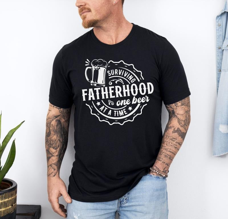 Surviving Fatherhood One Beer At A Time Shirt Funny Father Shirt Husband Shirt Fathers Day Gift Fatherhood Shirt Gift For Dad Funny TK43GN